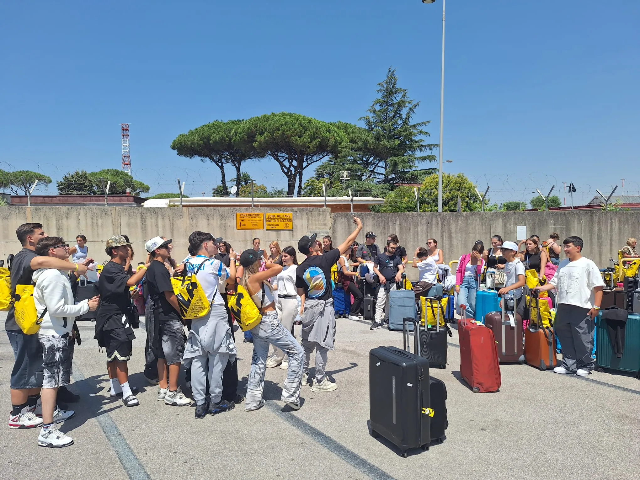 Il gruppo festeggia con le valigie nel piazzale dell’aeroporto di Capodichino, appena atterrati in Italia