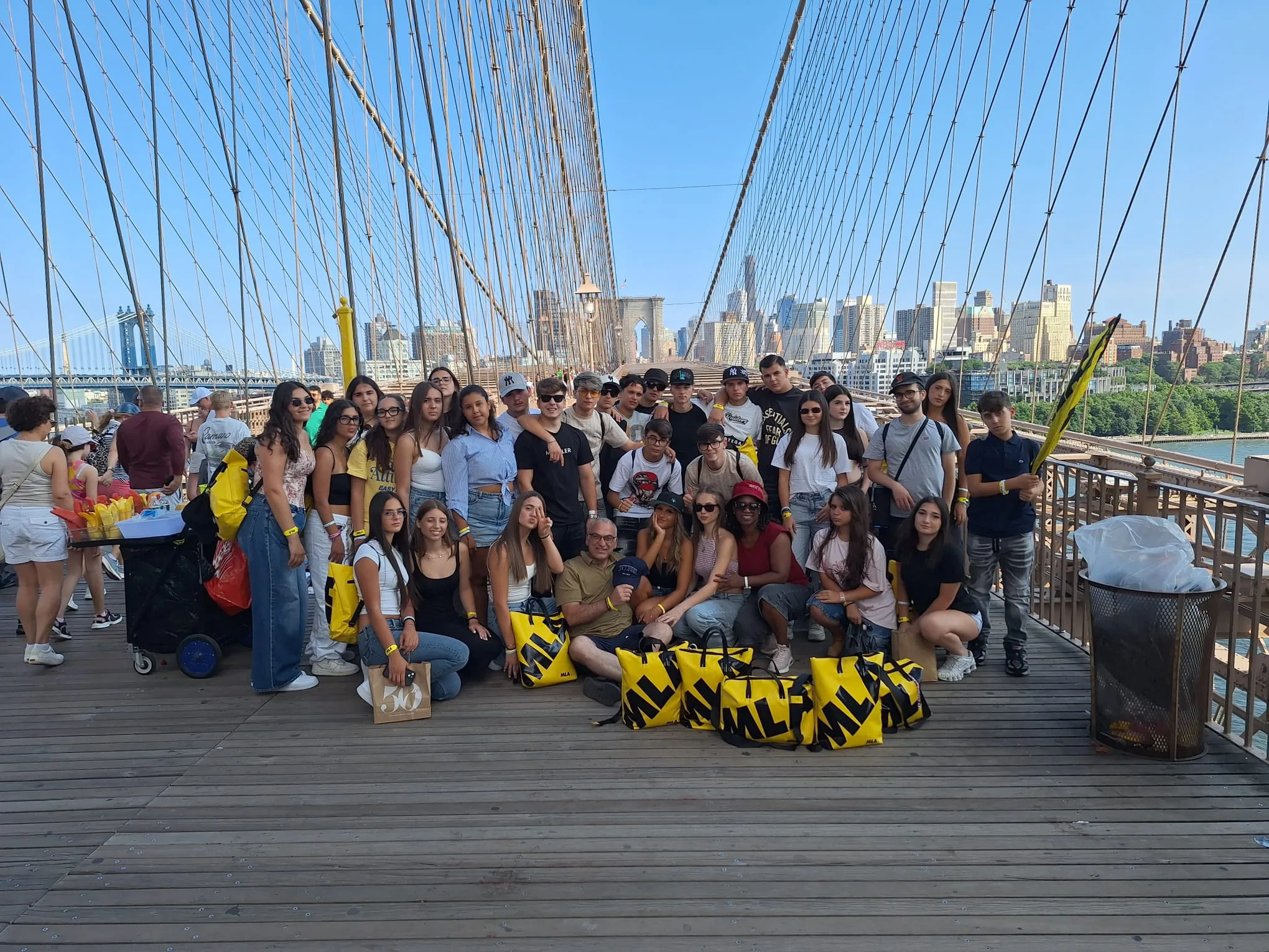 Foto di gruppo seduti sul ponte di Brooklyn con le borse MLA