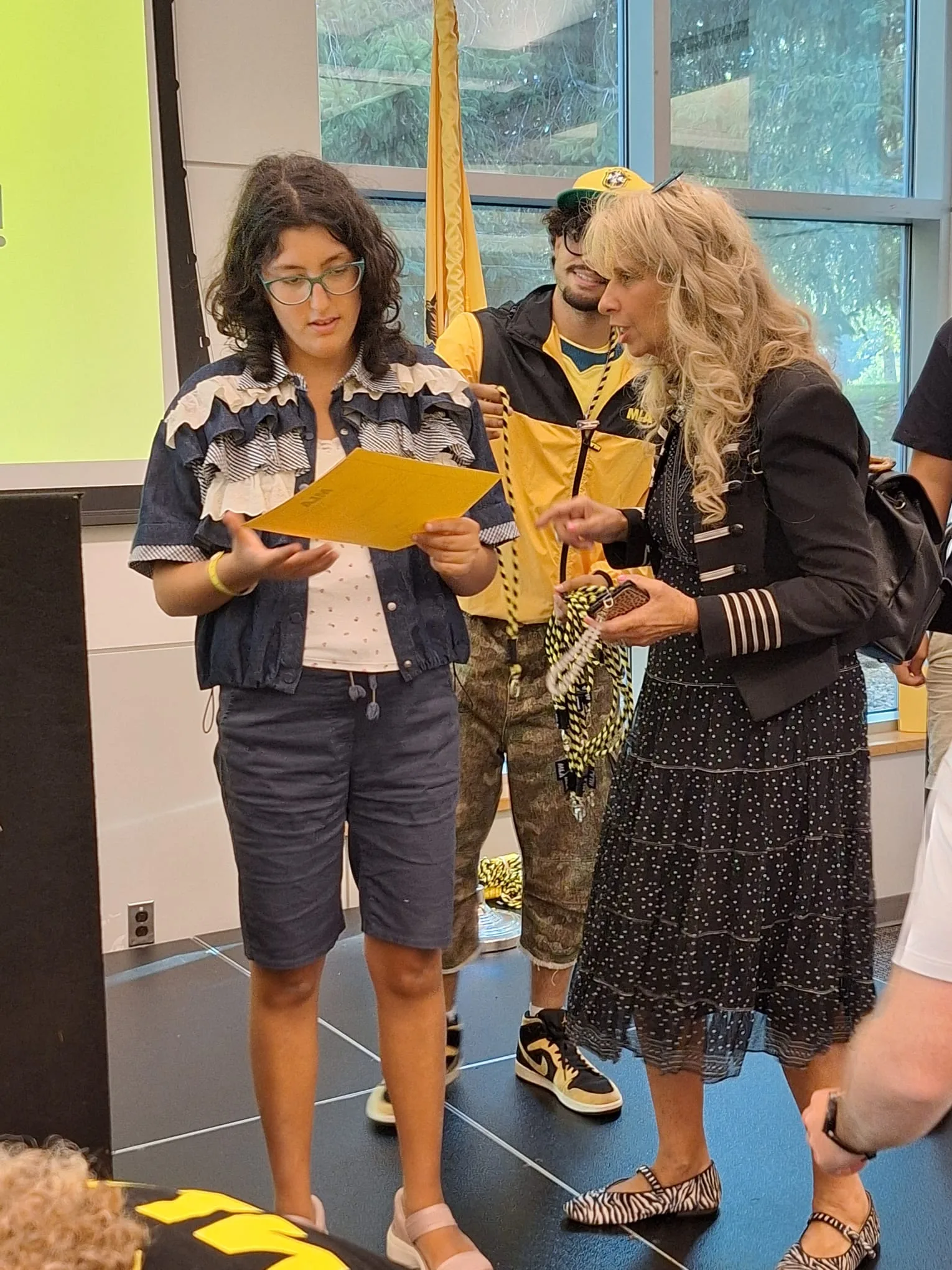 Una studentessa riceve il proprio diploma da un membro dello staff MLA