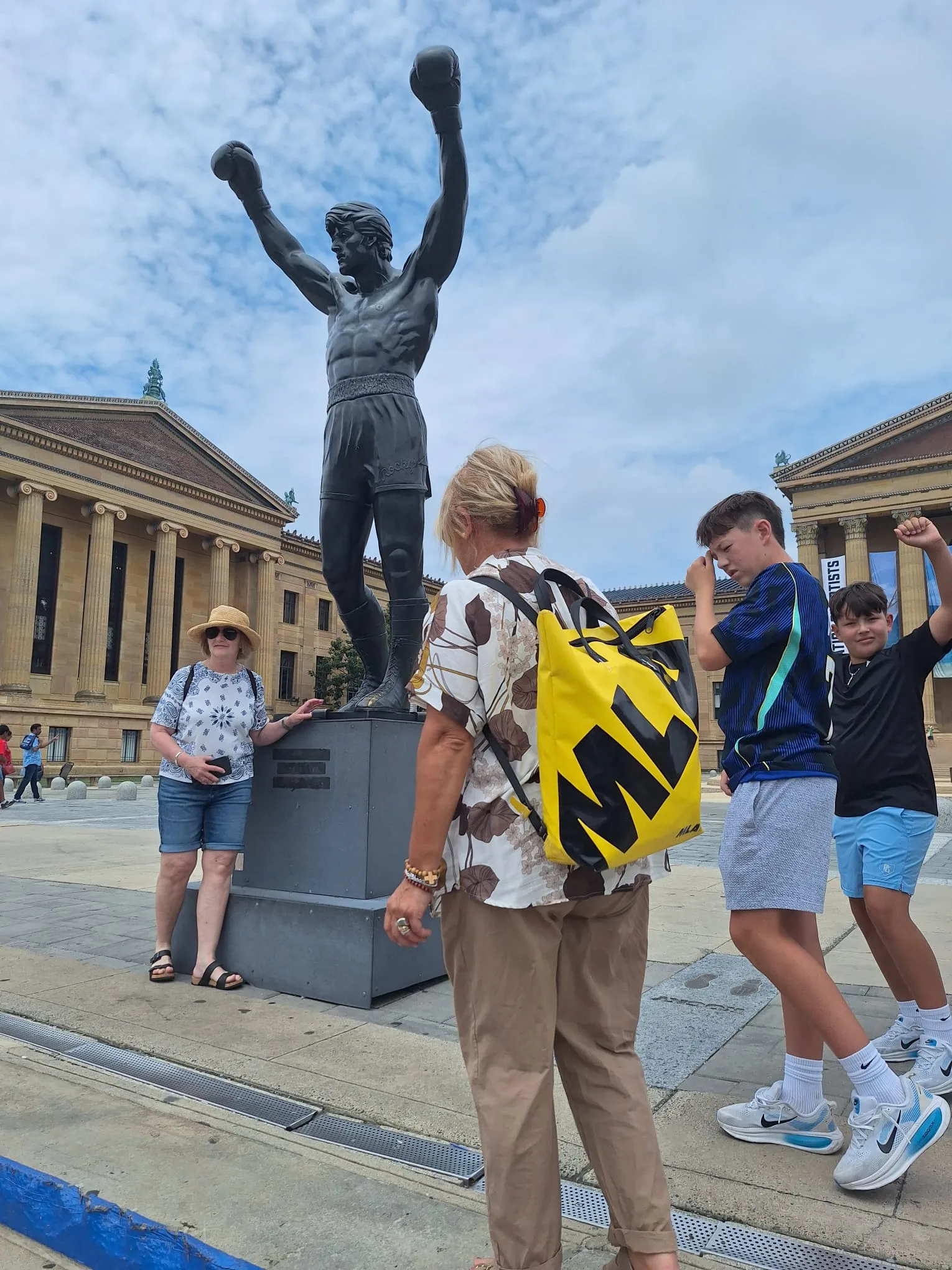 Staff MLA e studenti con zaino giallo in posa davanti alla statua di Rocky Balboa